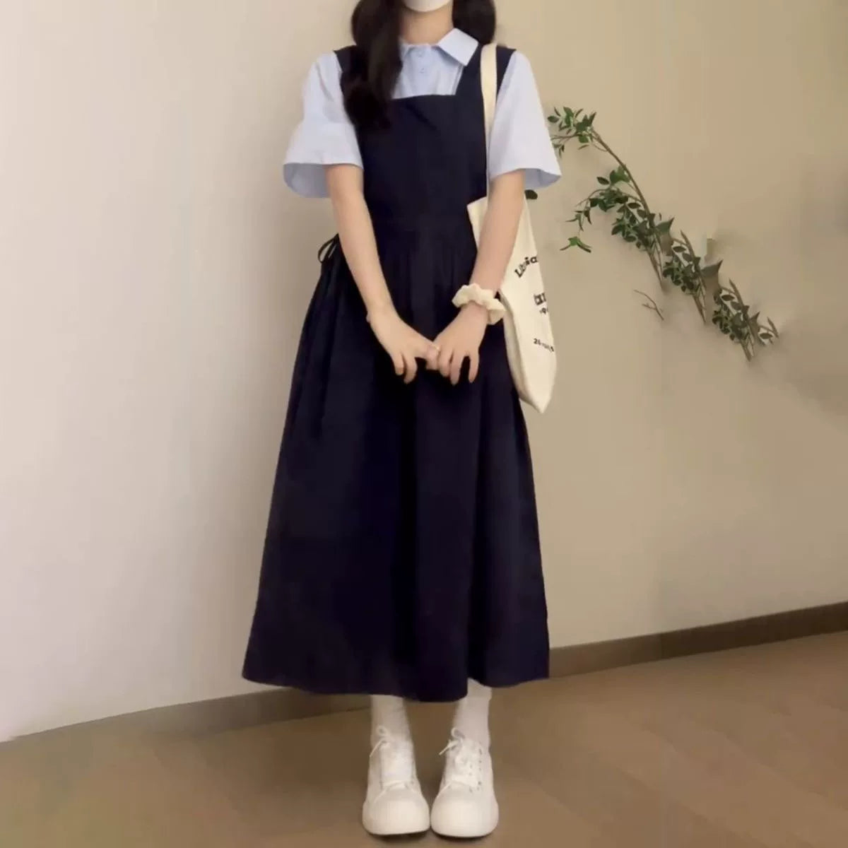 Yay hazırlığı üslubunda, geniş bədən quruluşlu, arıqladıcı kvadrat yaxalı, tünd göy rəngli asma don, qız tələbələr üçün uyğundur, mavi rəngli çoxfunksiyalı köynəklə üst-üstə düşmüşdür.